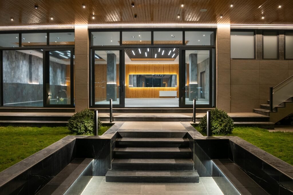 Elegant illuminated entrance to a modern luxury house at night with landscaped garden.