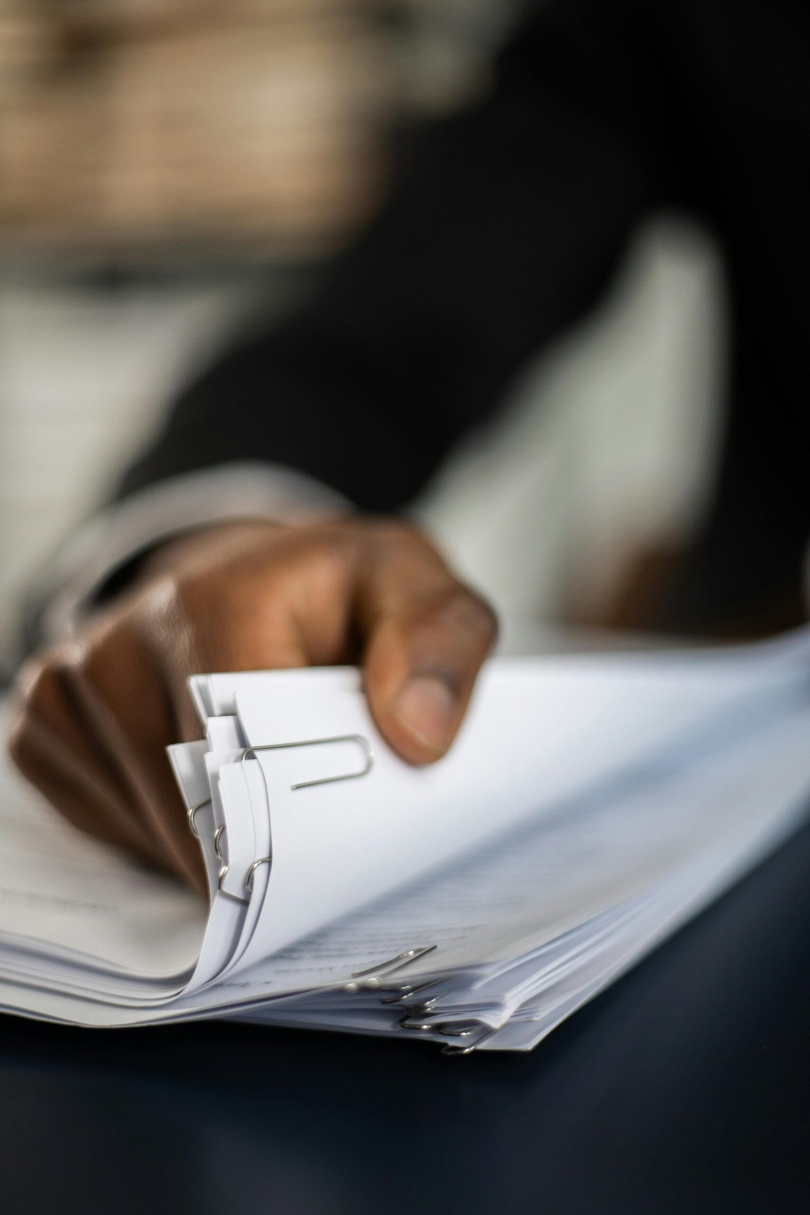 Close-up of hand organizing documents with paper clips, business focus.