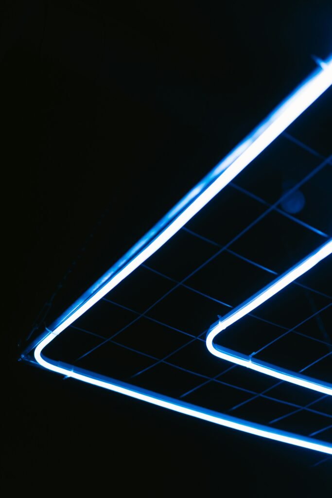 Abstract view of blue neon lights forming geometric patterns against a dark background.